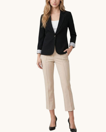 Woman wearing a black blazer and beige pants on a white background.