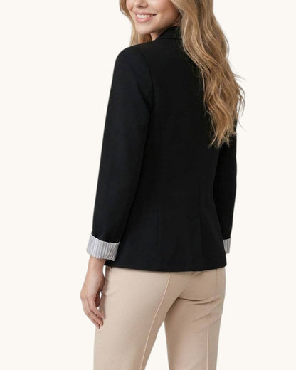 Woman wearing a black blazer with striped cuffs on a white background.