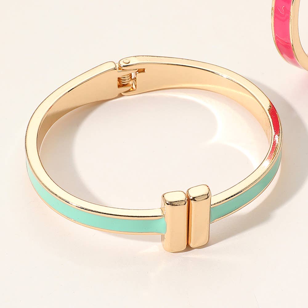 Gold and turquoise bangle with T shape at end on a white background.