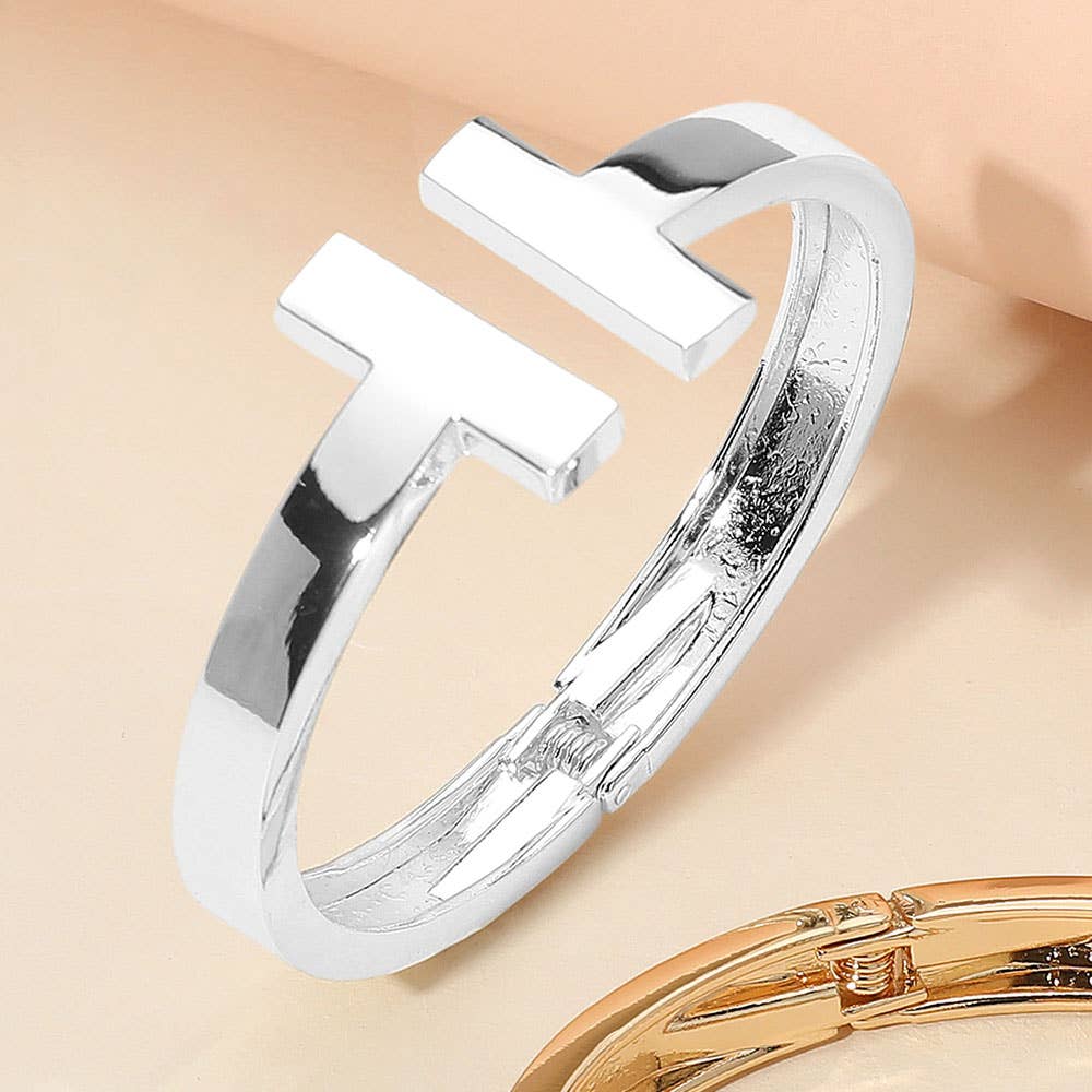 Silver cuff hinge bangle bracelet on a beige background.