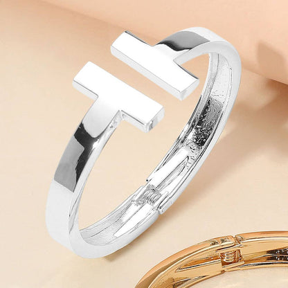 Silver cuff hinge bangle bracelet on a beige background.