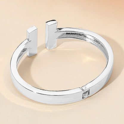 Silver cuff hinge bracelet on a beige background.