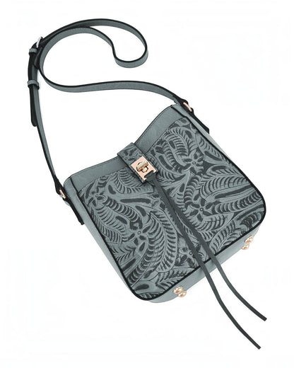 A blue-gray crossbody handbag with a darker tone embossed leaf pattern, matching detachable strap, and a gold-tone metal clasp, shown on a plain white background.