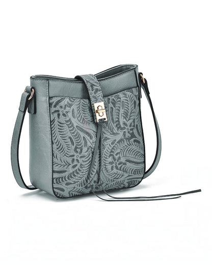 A slate blue leather crossbody bag with a detailed embossed floral and leaf pattern on the front flap, featuring a gold-tone metal clasp and a matching leather shoulder strap, shown on a plain white background.
