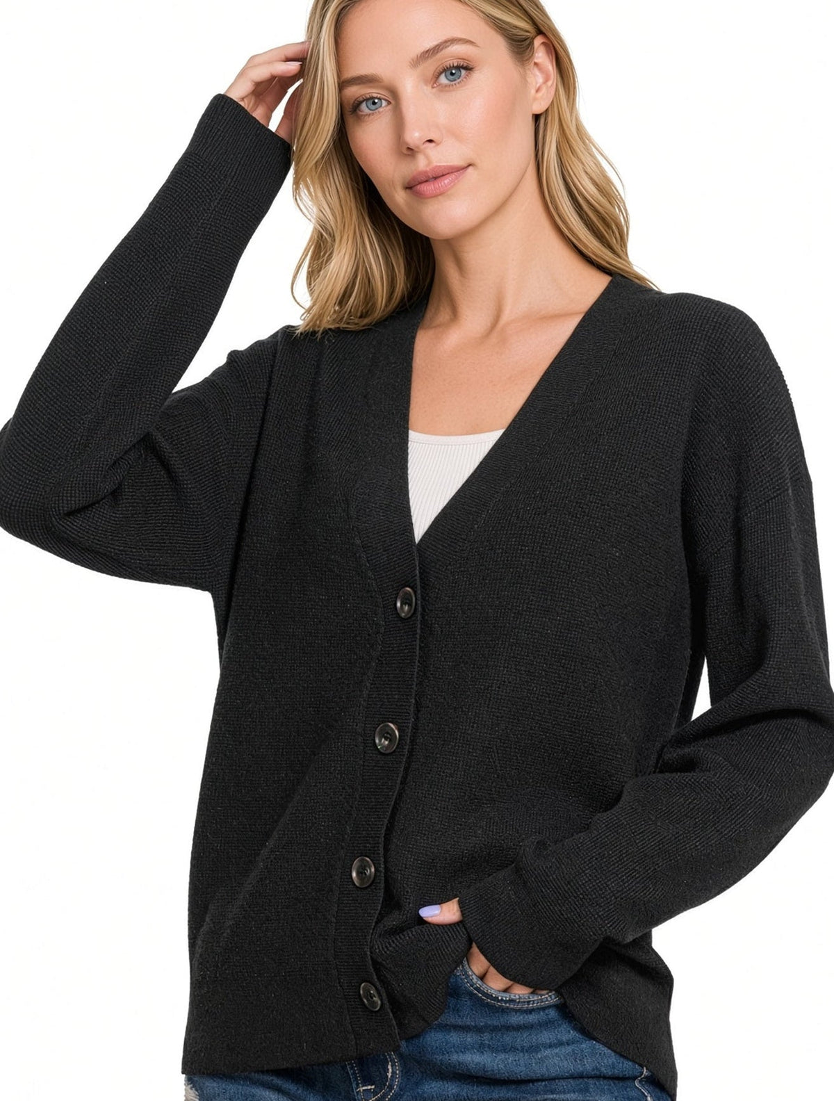 Woman wearing a black button front cardigan sweater over a white tee shirt with blue jeans.