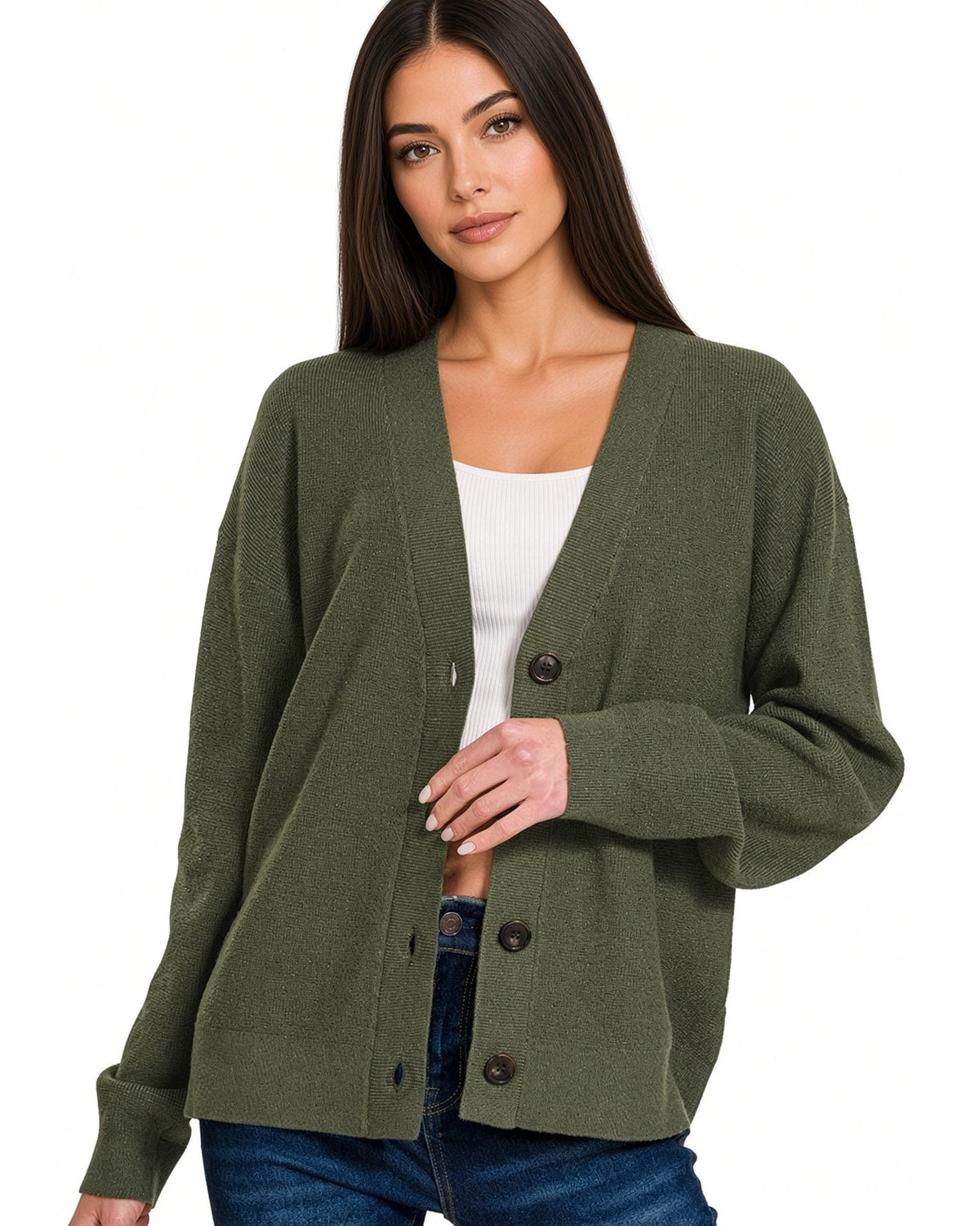 Woman wearing a dark olive button front medium length cardigan over a white cropped tee shirt and blue jeans. 