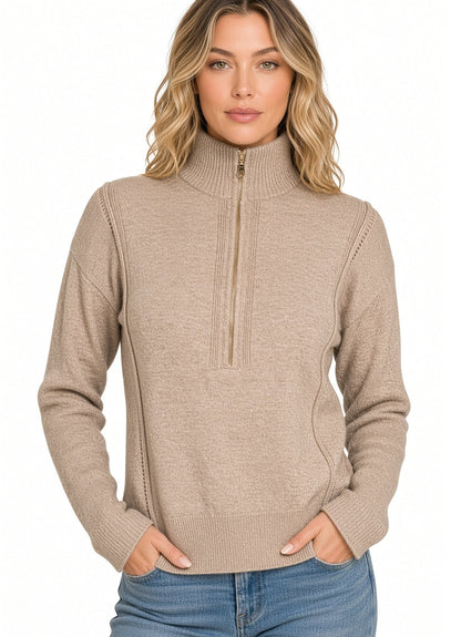A woman modeling a heather beige/mocha ribbed knit mock neck quarter zip sweater with side pockets, paired with blue jeans against a plain white background.