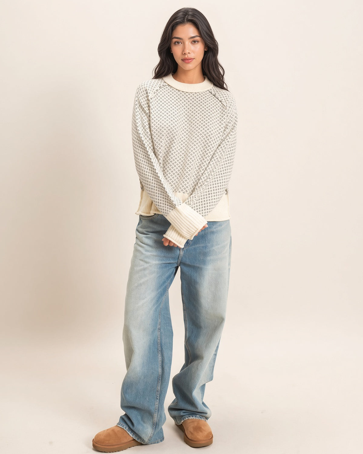 Full-length view of model wearing cream and charcoal birdseye knit sweater with light-wash wide-leg jeans.
