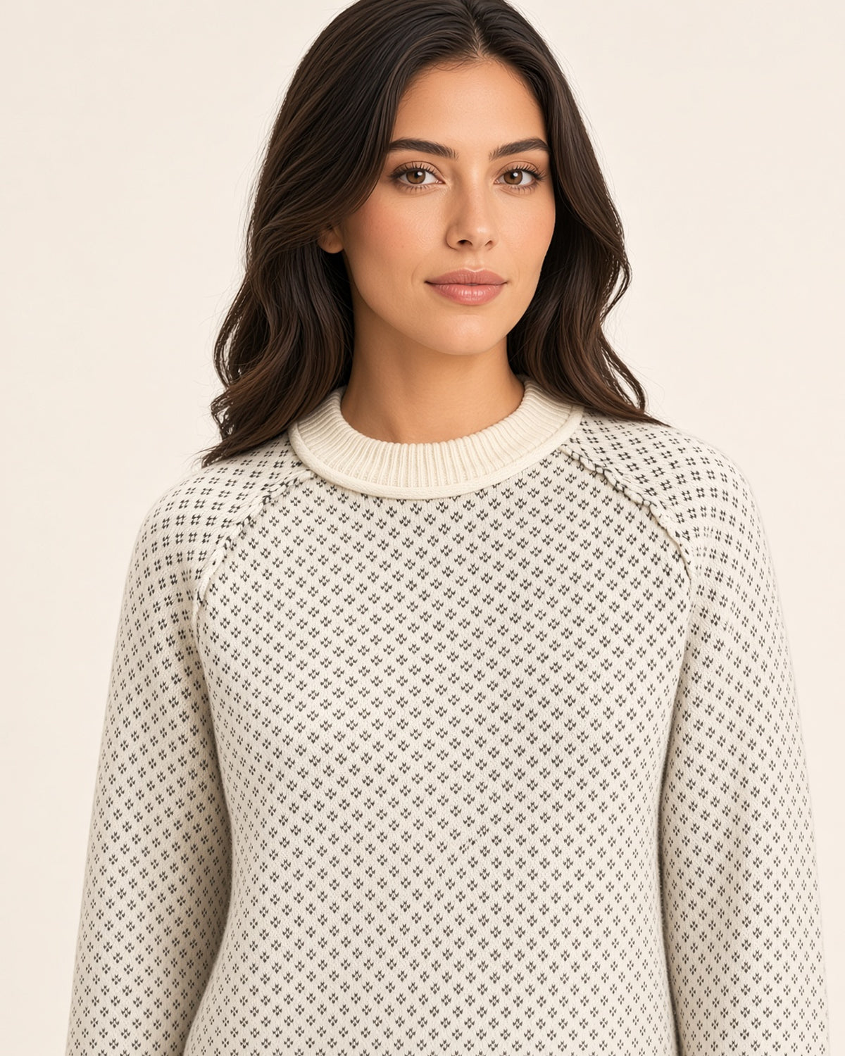 Close-up of charcoal birdseye knit pattern on cream sweater with ribbed neckline and raglan seams.
