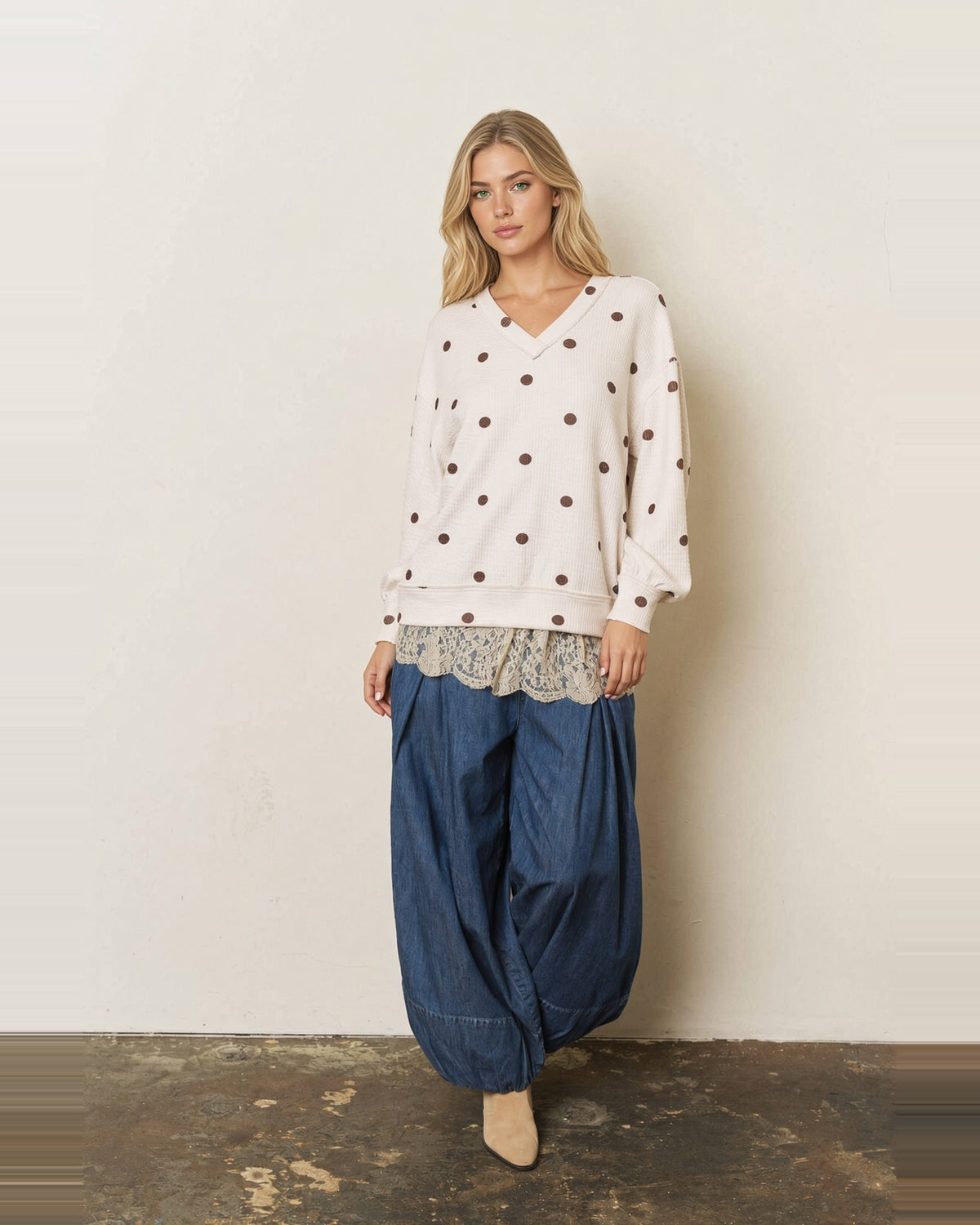 Full-length view of a model wearing the Sweet Spot cream and brown polka dot V-neck top with blue wide-leg pants.
