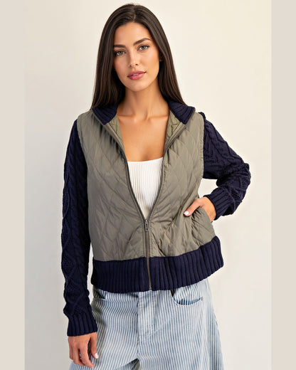 Navy and olive mixed-media jacket with quilted body, navy cable knit sleeves, and ribbed trim with a zipper front.