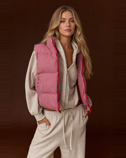Front view of model wearing a red and white gingham cropped puffer vest open over a light gray hoodie.