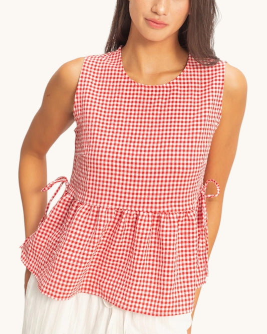Red and white checkered sleeveless top worn by a person on a white background