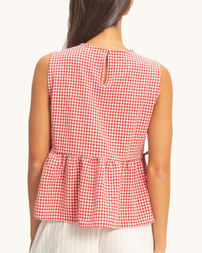 Red and white checkered sleeveless top worn by a person on a white background