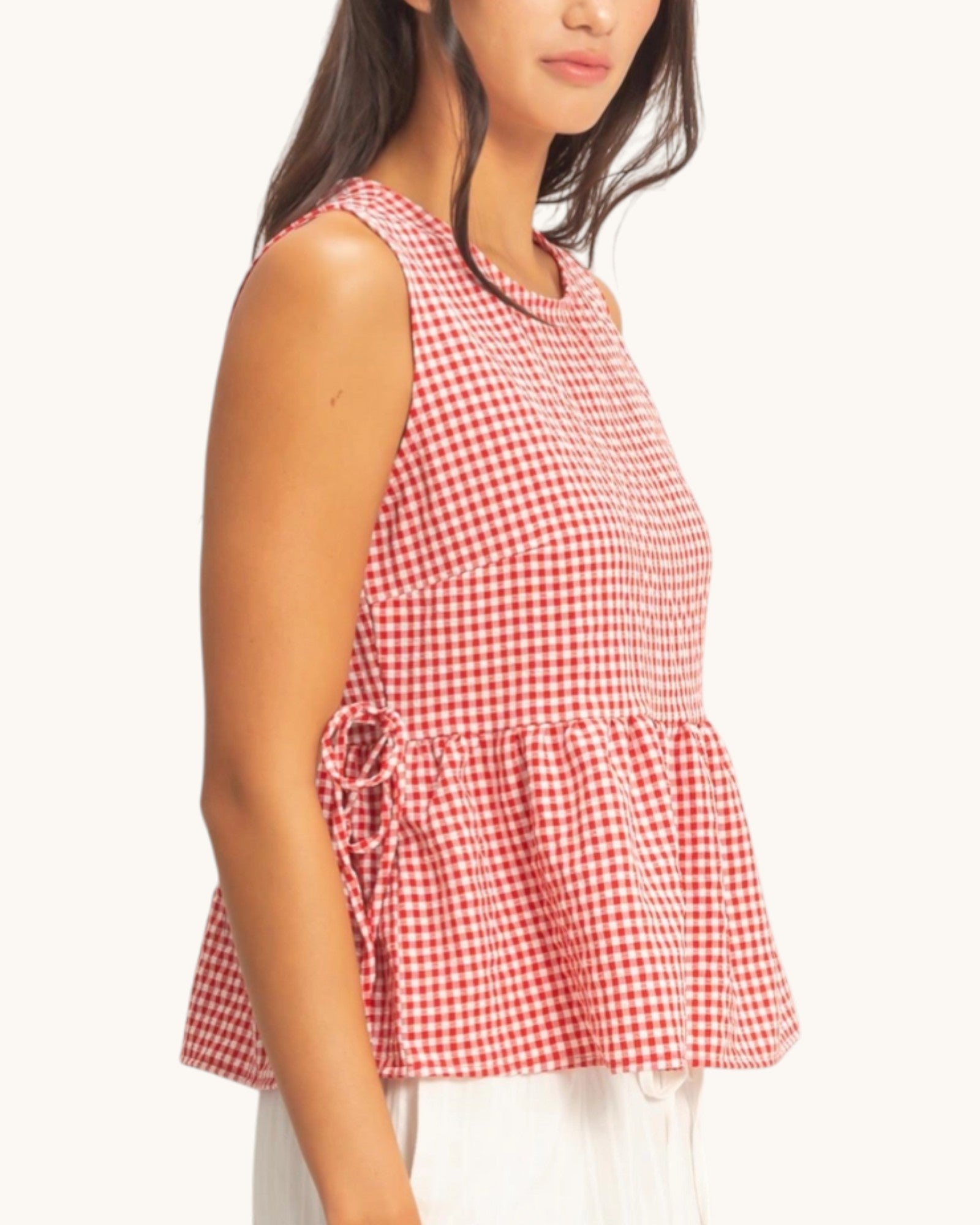 Red and white checkered sleeveless top worn by a person on a white background