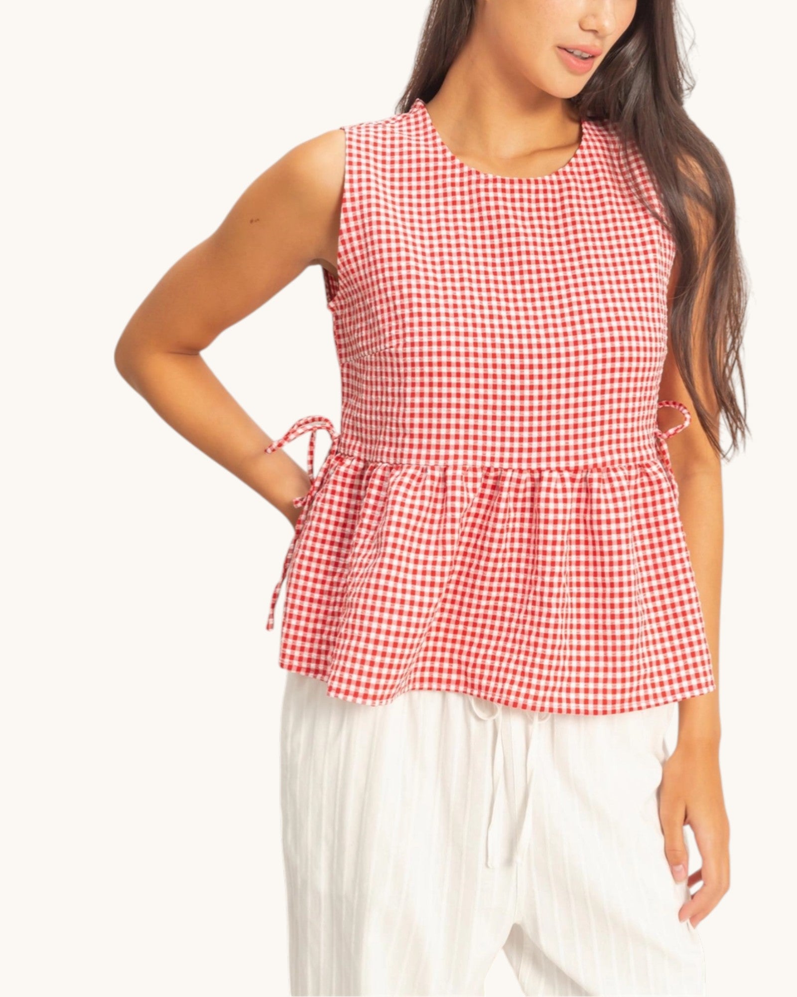 Red and white checkered sleeveless top worn by a person on a white background