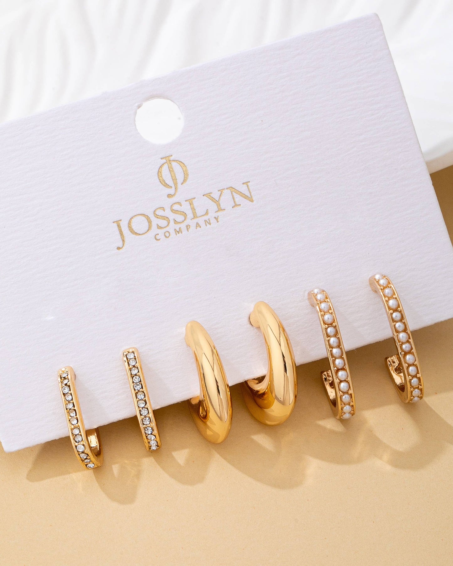 Set of 3 gold hoop earrings on a JOSSLYN Company branded card.