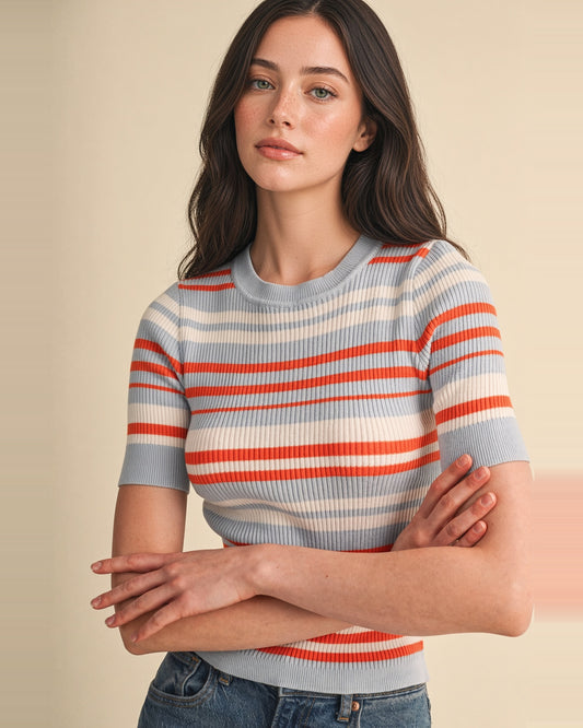A woman wearing a short-sleeve ribbed knit sweater with horizontal stripes in light blue, off-white, and orange, paired with blue jeans, set against a plain beige background.