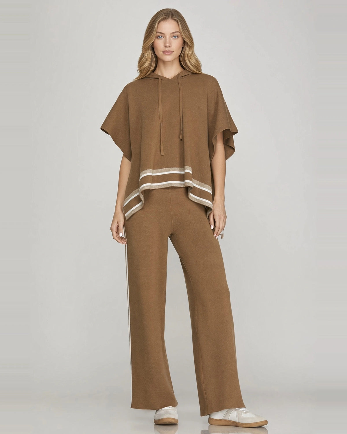 Full-length front view of model wearing mocha brown short sleeve knit hoodie cape with contrast striped hem and matching pants.