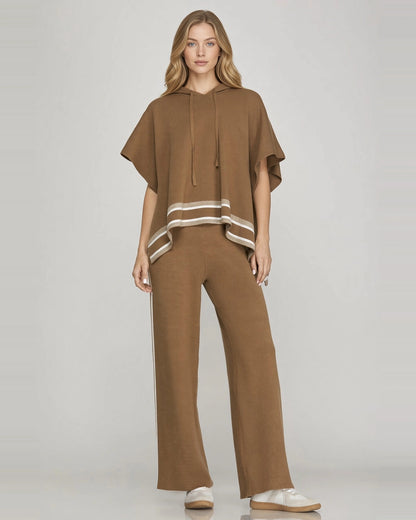 Full-length front view of model wearing mocha brown short sleeve knit hoodie cape with contrast striped hem and matching pants.