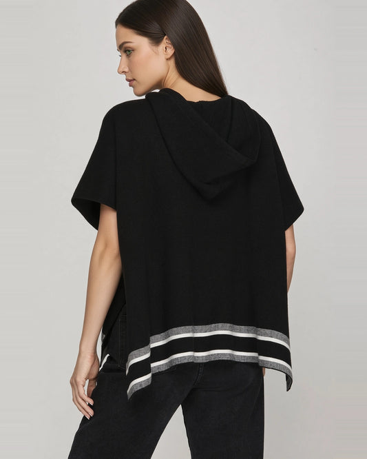 Back view of black short sleeve knit hoodie cape showing hood, roomy silhouette, and gray and white striped hem.