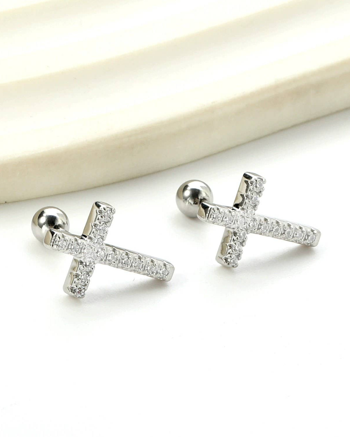 Silver cross shaped rhinestone earrings on a white background.