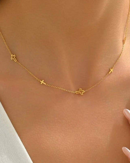 Gold necklace with small crosses on a person's neck.