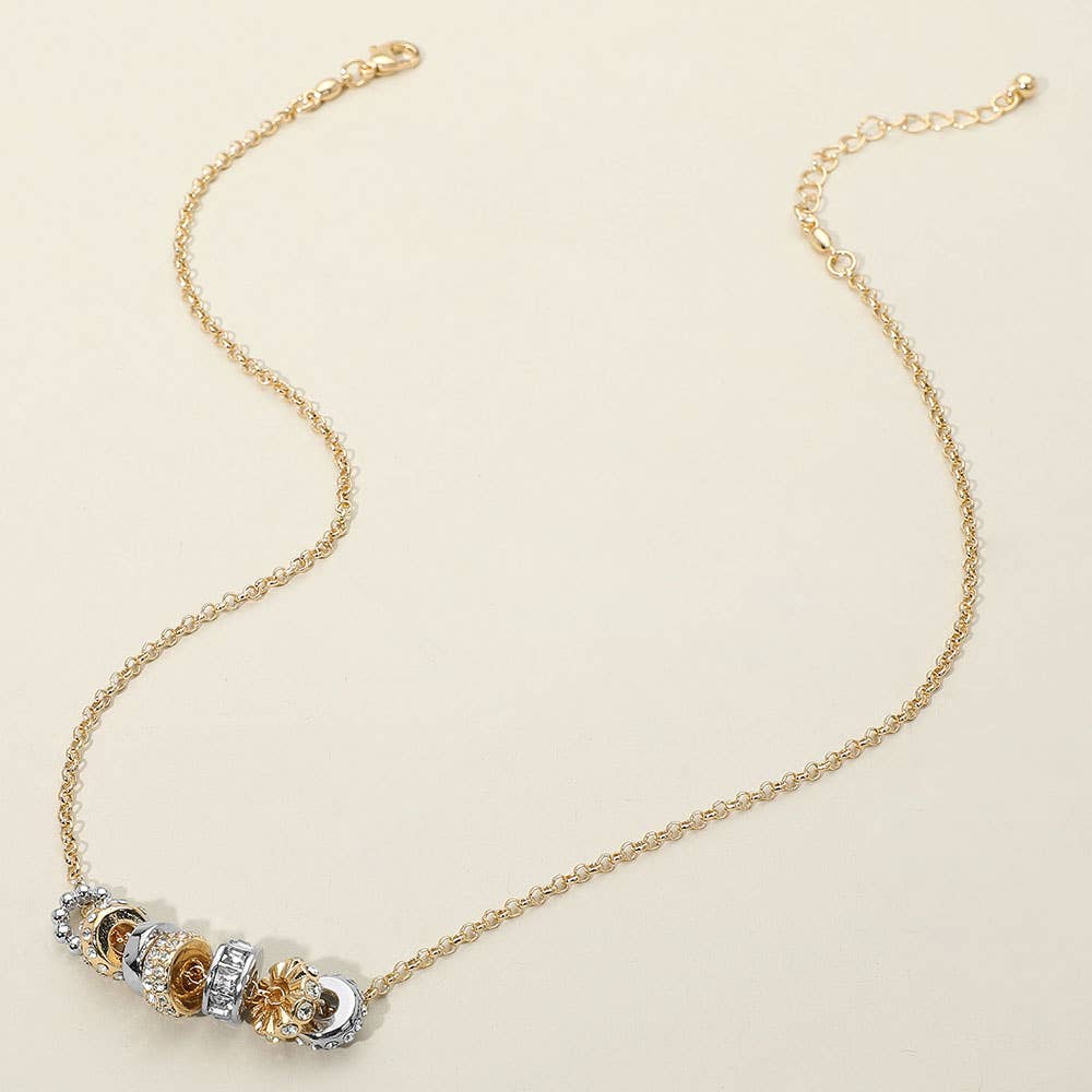 Gold necklace with gold and silver decorative elements on a beige background.