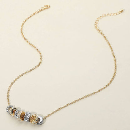 Gold necklace with gold and silver decorative elements on a beige background.