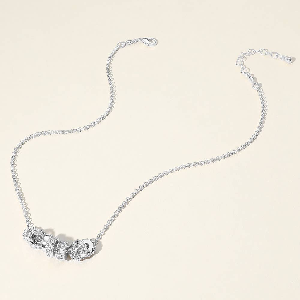 Silver necklace with ring pendants on a light background.