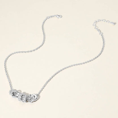 Silver necklace with ring pendants on a light background.