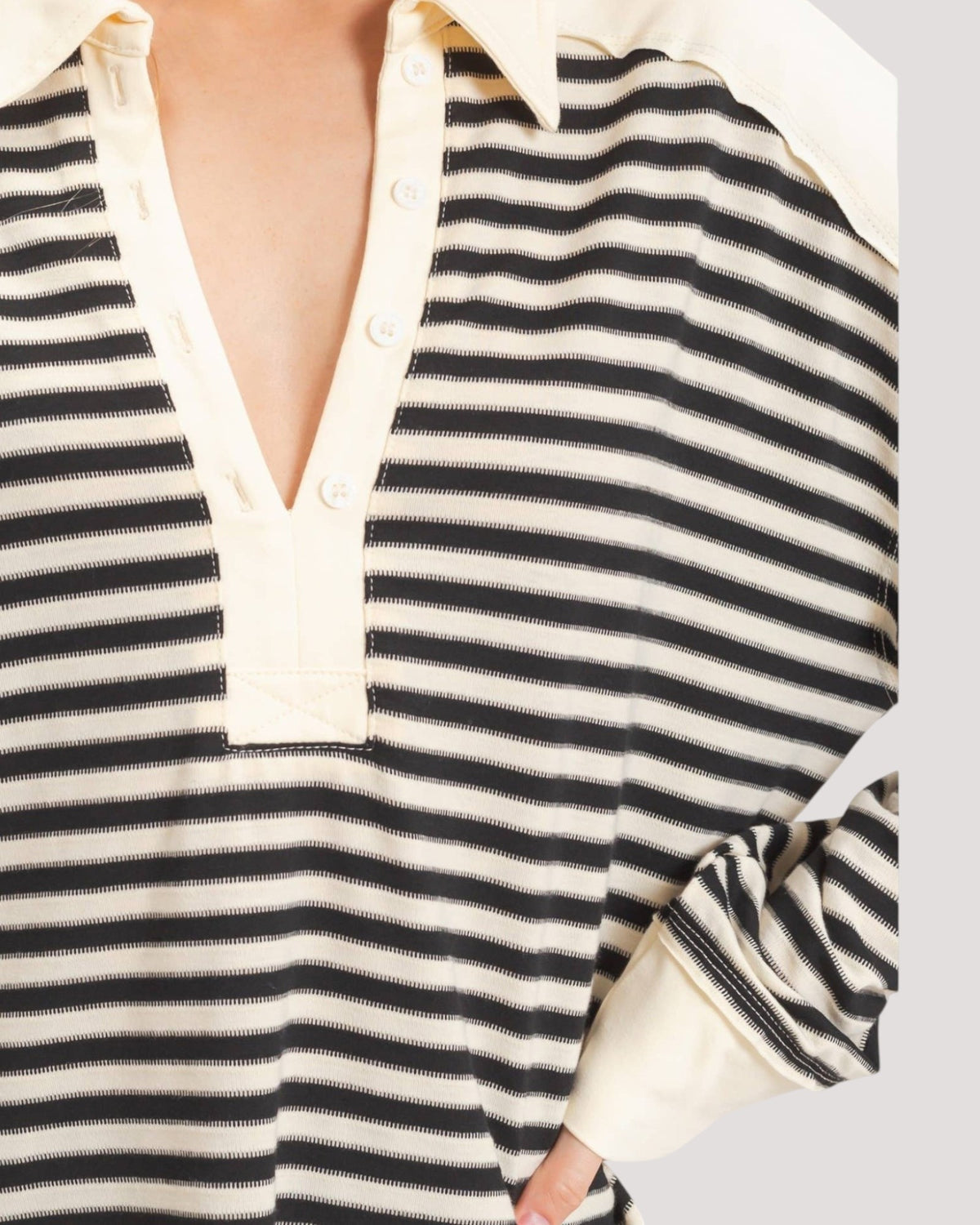 Close-up of a striped long-sleeve rugby shirt with a cream collar and button placket, worn by a model.