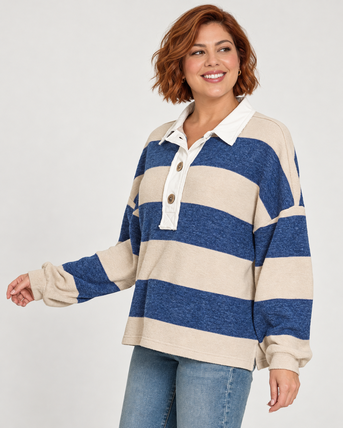 Woman wearing a blue and light tan long sleeve shirt with wide horizontal stripes and contrast cream collar and placket with 3 buttons and blue jeans.