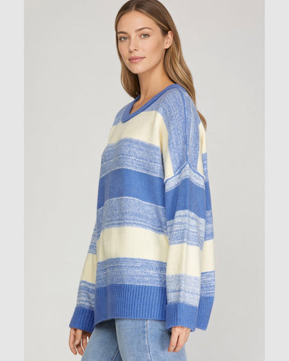 Angled view of blue and cream striped oversized knit sweater with dropped shoulders and blue ribbed trim.