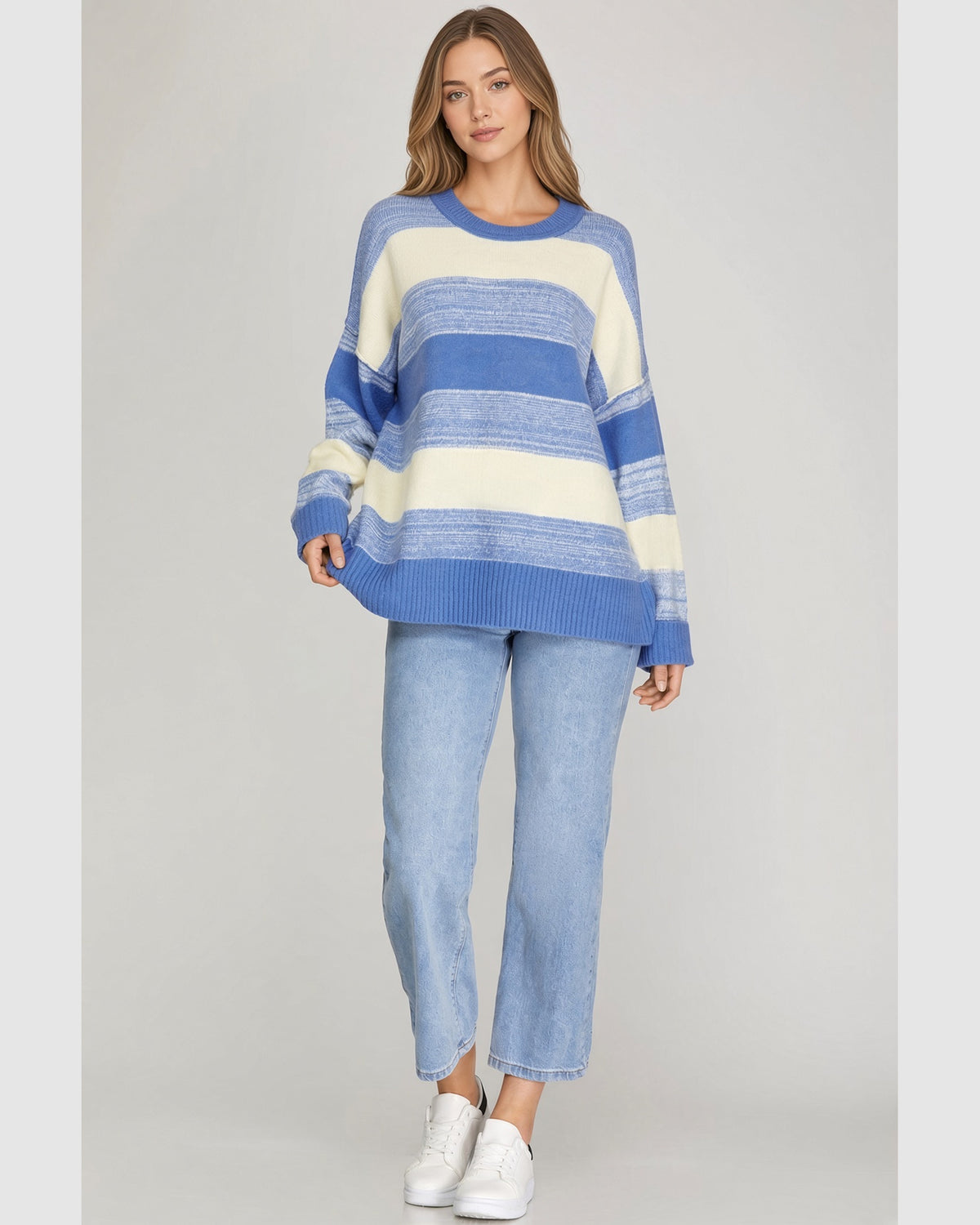 Full length view of the blue and cream knit sweater worn with blue jeans.
