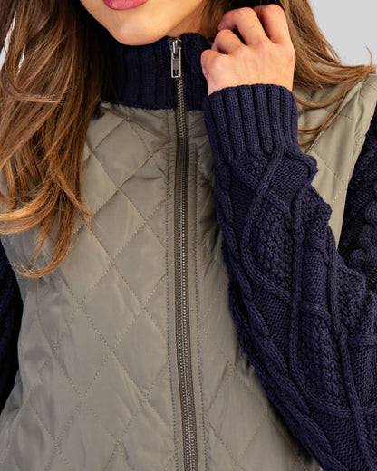Close up of an olive quilted body and navy cable kit sleeves with silver zipper.