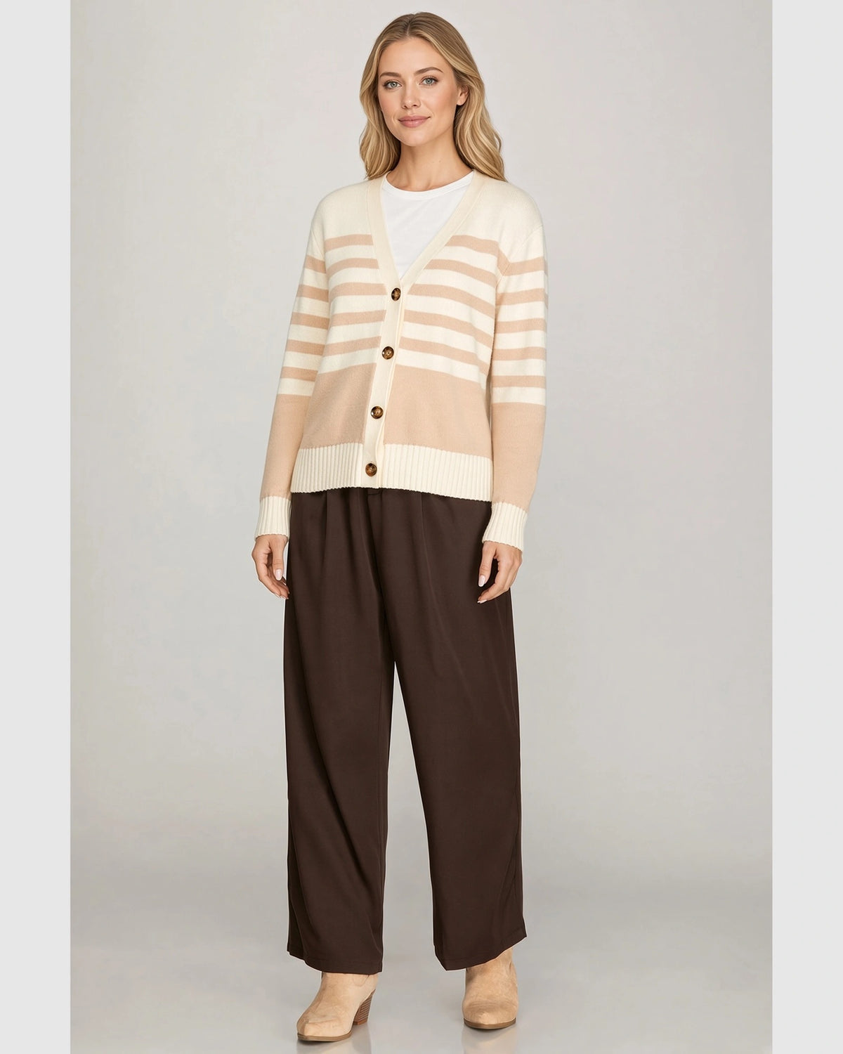 Model outdoors wearing taupe and cream striped cardigan with cream ribbed cuffs and hem.