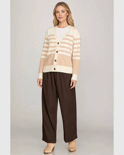 Model outdoors wearing taupe and cream striped cardigan with cream ribbed cuffs and hem.