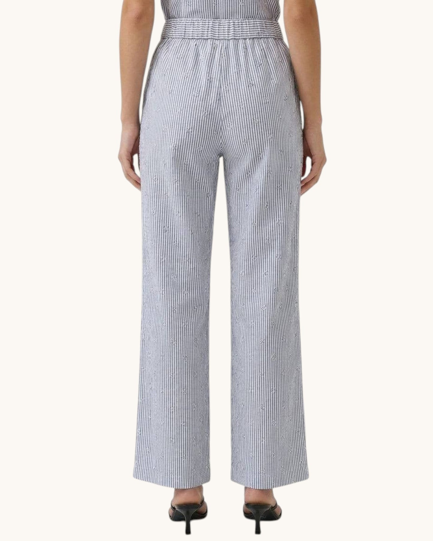 Woman wearing a black and white striped linen pant on a white background.