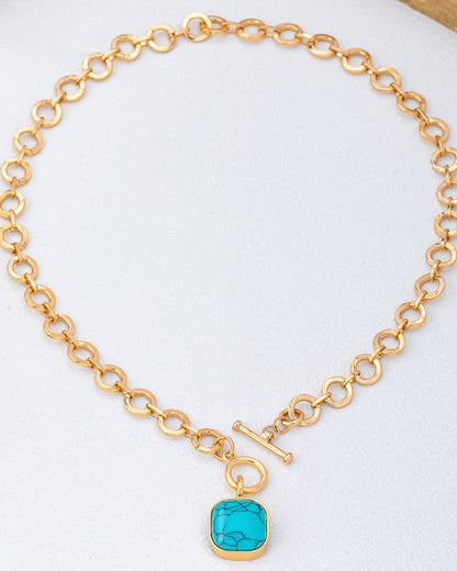 Gold chain toggle necklace with a turquoise pendant on a white background.