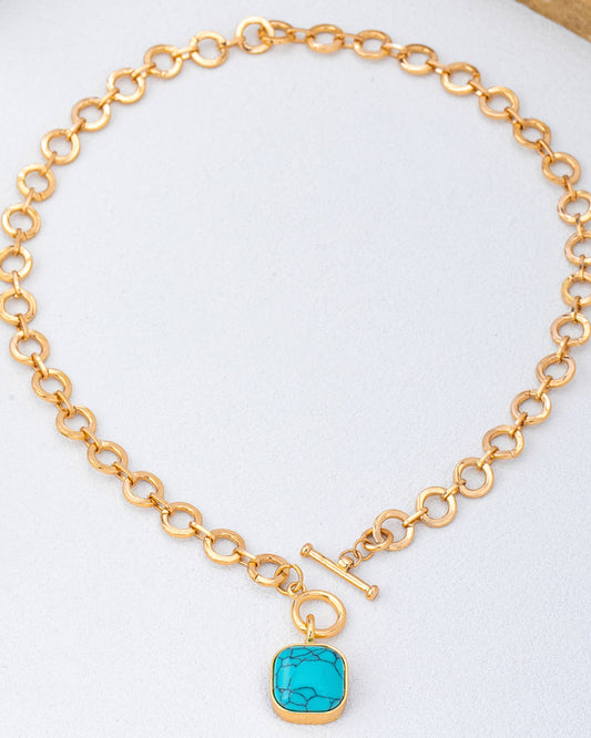 Gold chain toggle necklace with a turquoise pendant on a white background.