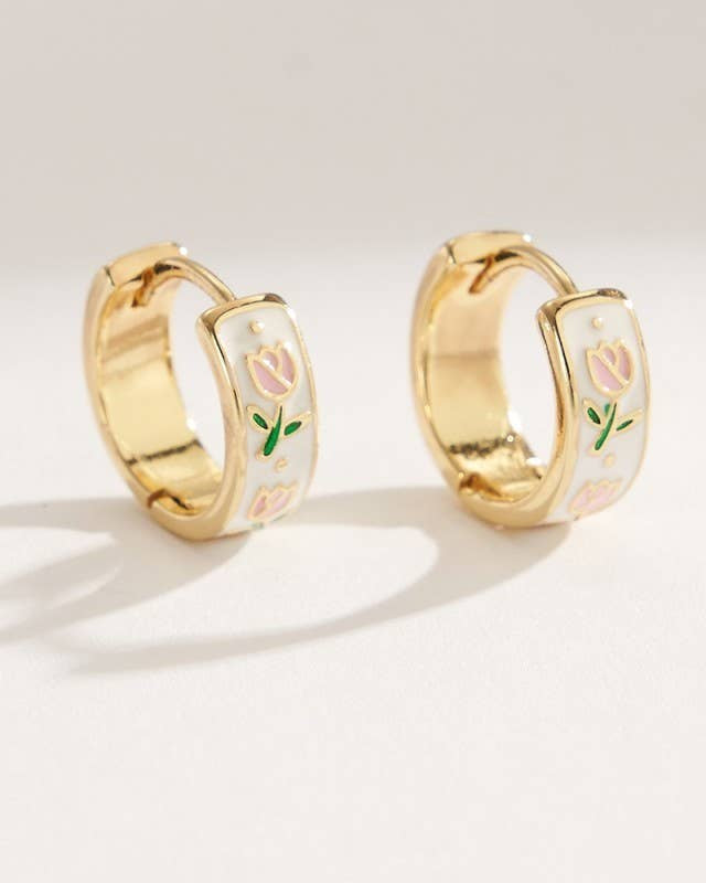 Gold hoop earrings with floral design on a light background.