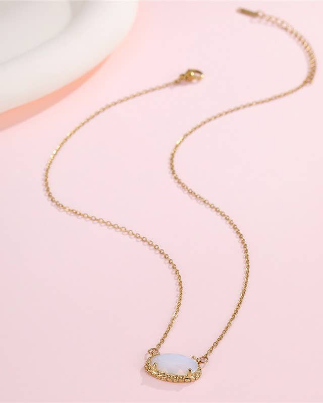 Gold necklace with a white jade pendant on a pink background.