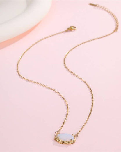 Gold necklace with a white jade pendant on a pink background.