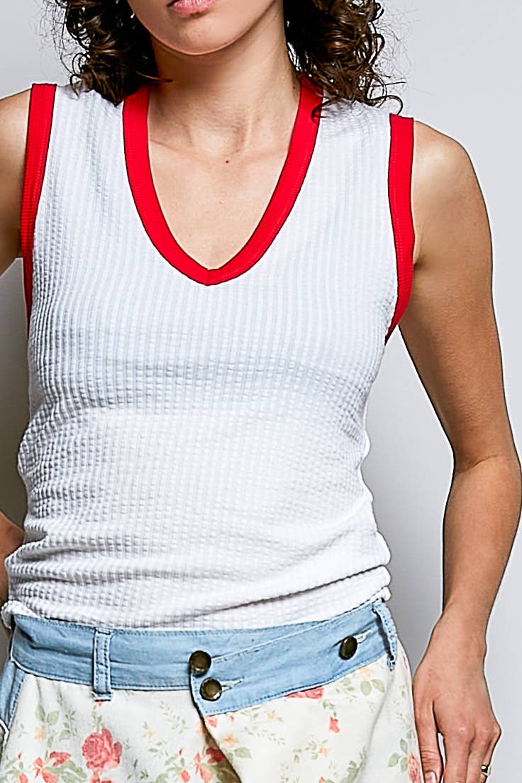 Person wearing a white ribbed tank top with red trim against a plain background.