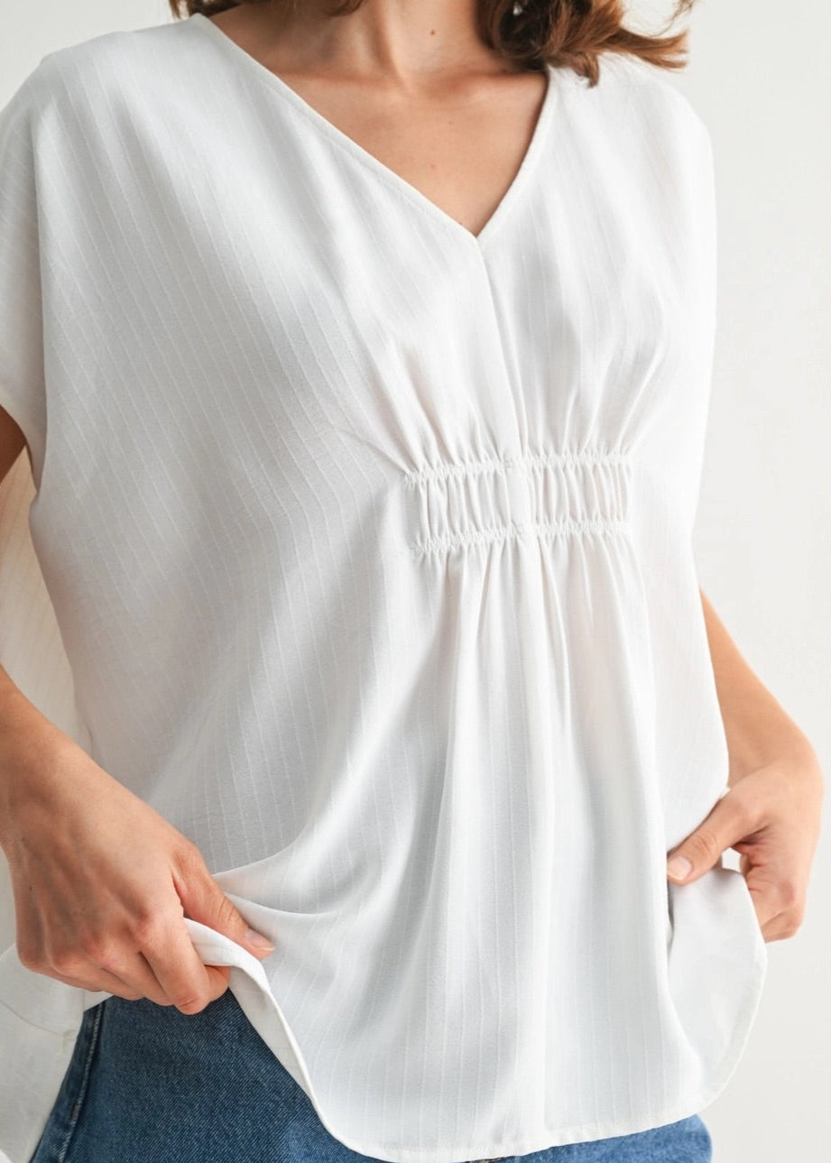 White V-neck tunic with smocking and subtle stripe texture.
