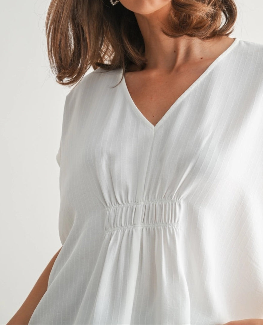 White V-neck tunic with smocking and subtle stripe texture.