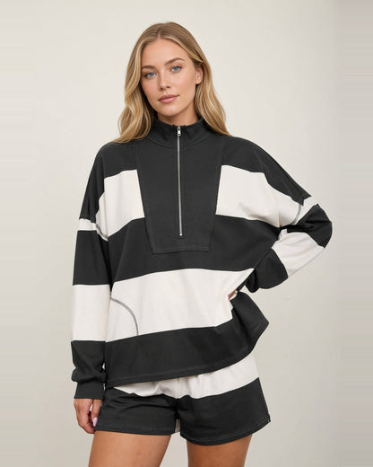 Front view of the Rally Stripe top with wide charcoal and ivory stripes, a half zipper, and tall collar.