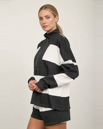 Side view of the Rally Stripe half-zip top, showing dropped shoulders, wide stripes, and ribbed cuffs.